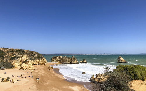Sandstrand mit Felsen und blauem Himmel an der Algarve, Portugal.