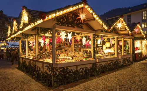 Beleuchteter Weihnachtsmarktstand mit Dekorationen und Waren bei Nacht.