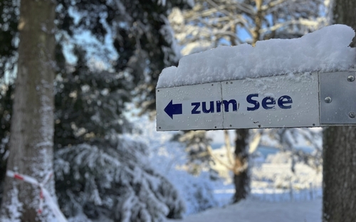 Schneebedecktes Wegweiser-Schild mit Schrift 