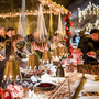 Marktstand mit weihnachtlicher Dekoration und Besuchern im Kerzenlicht.