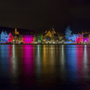 Beleuchtete Häuser am Moselufer bei Nacht, reflektiert im Wasser.