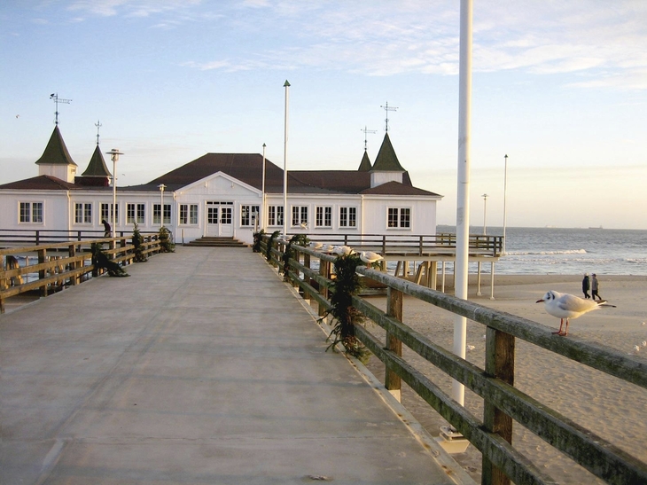 Seebrücke mit Haus am Strand von Ahlbeck bei Sonnenuntergang.