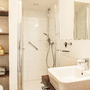 Helles Badezimmer in der Ferienanlage Büsum, mit Dusche, Waschbecken und Handtuchregal.