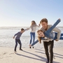 Familie spaziert fröhlich am Strand der Nordsee im Herbst oder Winter.