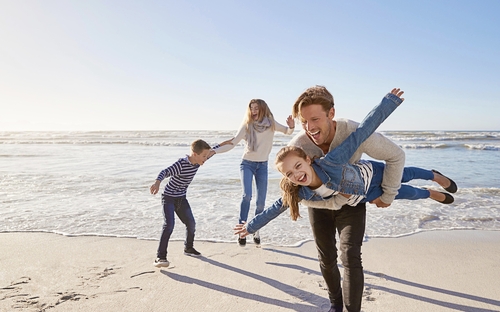 Familie spaziert fröhlich am Strand der Nordsee im Herbst oder Winter.