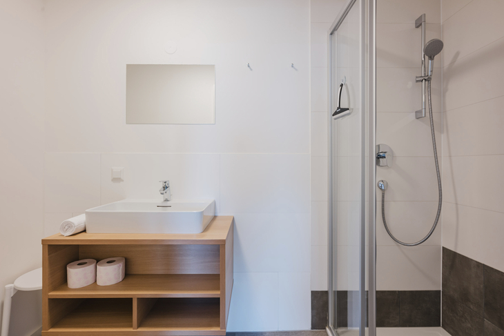 Badezimmer mit Waschbecken, Spiegel und Duschkabine in einem modernen Design.