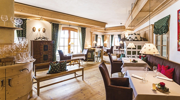 Gemütliches Restaurant mit Holzeinrichtung und gedeckten Tischen im Schlosshotel Kitzbühel.