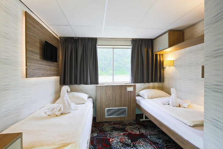 Zwei Einzelbetten in einem Kabinenzimmer mit Fenster auf einem Flusskreuzfahrtschiff.