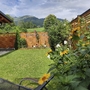 Garten eines Bungalows mit Blumen, Holzzaun und Bergblick im Hintergrund.