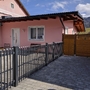 Vorderansicht eines rosa Bungalows mit Zaun und Einfahrt im Vordergrund.