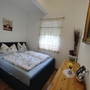 Kleines Schlafzimmer mit Doppelbett, Holztisch, Bild an der Wand und Tageslichtfenster.