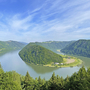 Blick auf die Schlögener Schlinge der Donau, umgeben von grünen Hügeln und bewaldeten Ufern.