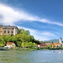 Blick auf eine Burg und eine Kirche am Ufer der Donau bei blauem Himmel.