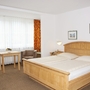 Helles Doppelzimmer mit Holzmöbeln und großem Fenster.