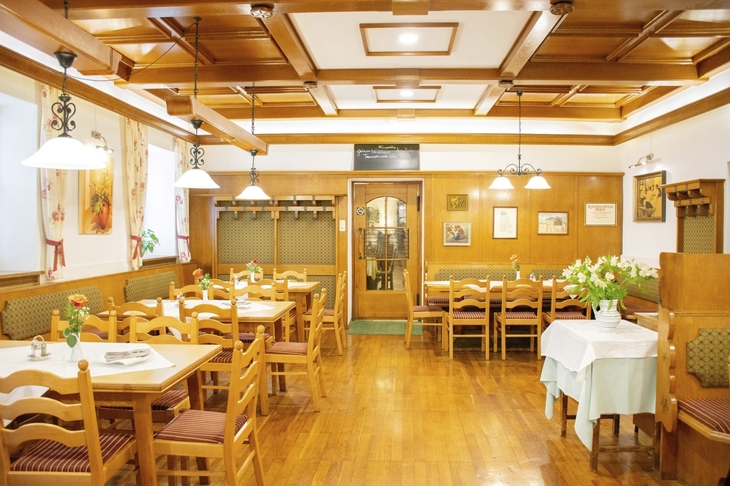 Restaurantbereich mit Holzmöbeln und blumengeschmückten Tischen im Landhotel Post Ebensee.