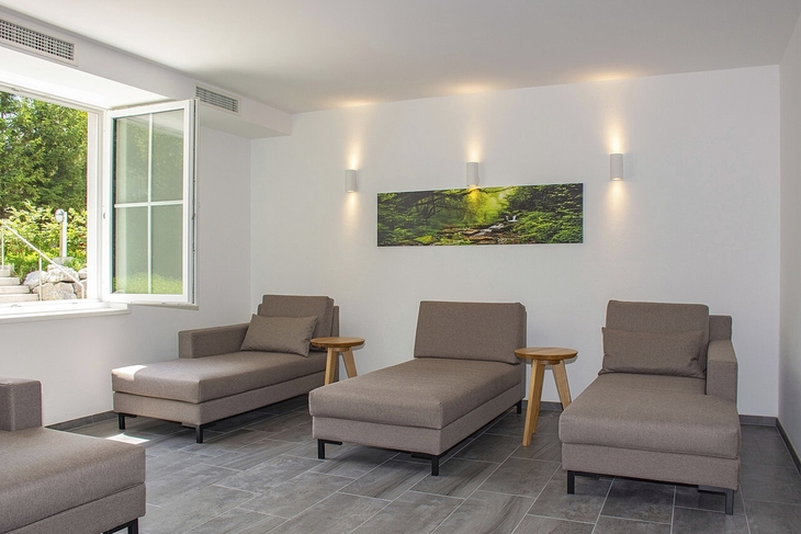 Moderner Wellnessbereich mit Liegen und dekorativem Wandbild.