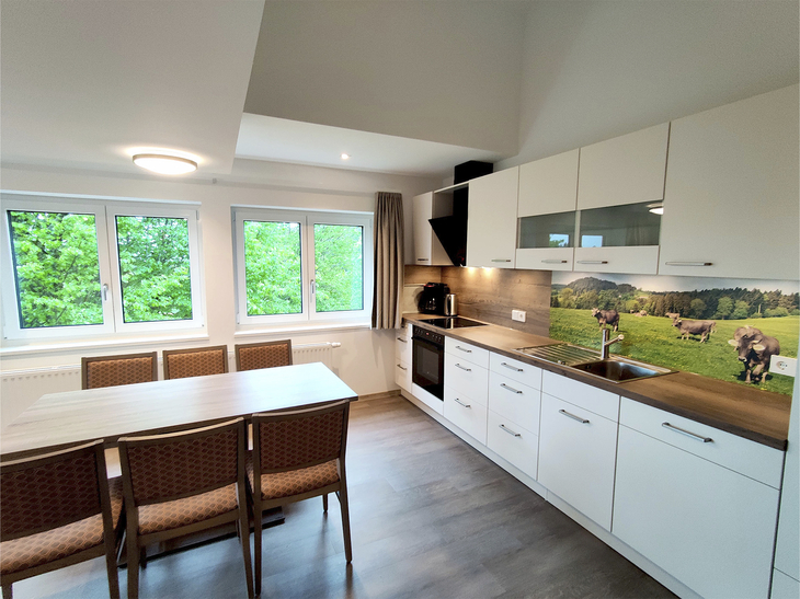Helle, moderne Küche mit Esstisch und großem Fenster.