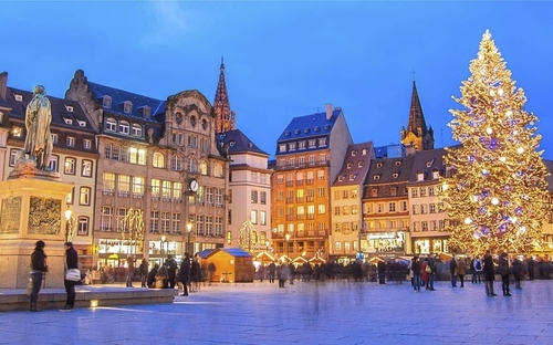 Straßburger Weihnachtsmarkt mit beleuchtetem Weihnachtsbaum und historischen Gebäuden.