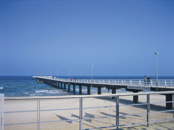 Steg am Timmendorfer Strand führt ins Meer bei klarem Himmel.