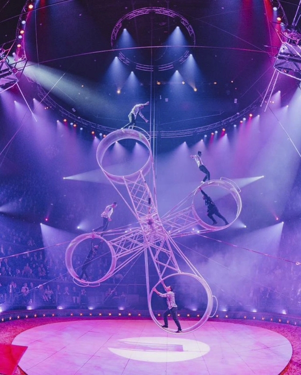 Artisten auf einem Todesrad unter pinkem Scheinwerferlicht im Weihnachtscircus.