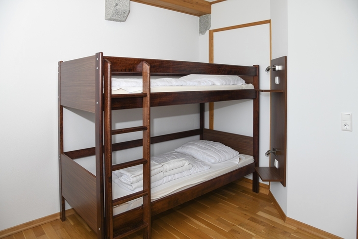 Stockbett in einem hellen Zimmer mit Holzfußboden und weißer Bettwäsche.