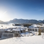 Winterliche Landschaft in Inzell mit verschneiten Gebäuden und Bergen im Hintergrund.