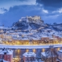 Blick auf das verschneite Salzburg mit Festung Hohensalzburg im Winter bei Abenddämmerung.