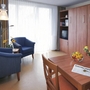 Wohnzimmer einer Ferienwohnung mit Sessel, Tisch, Fernseher und Blumendekoration.