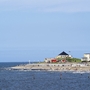 Küstenlandschaft mit Strand, Häusern und blauem Himmel.