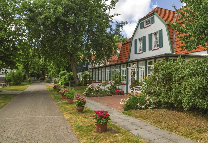 Haus auf Spiekeroog mit Garten und Allee im Sommer.