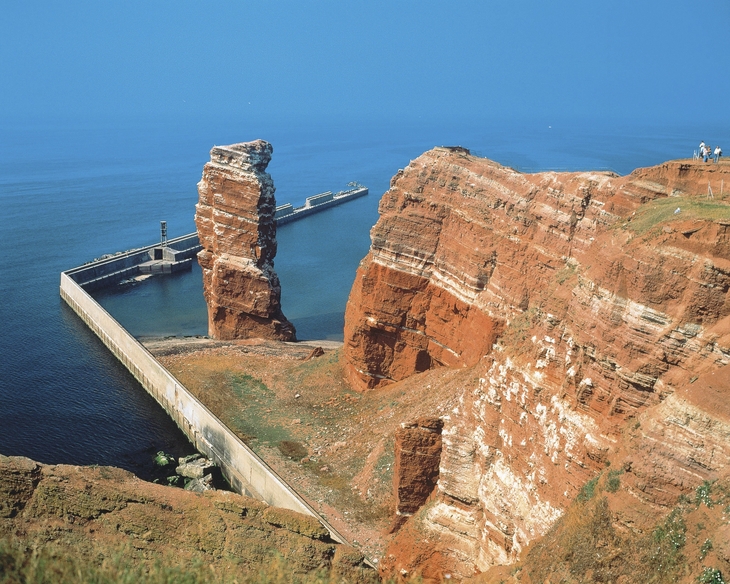 Rote Felsformation Lange Anna auf Helgoland im Meer bei blauem Himmel.