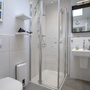 Modernes Badezimmer mit Dusche, Waschbecken, Toilette und Spiegel.