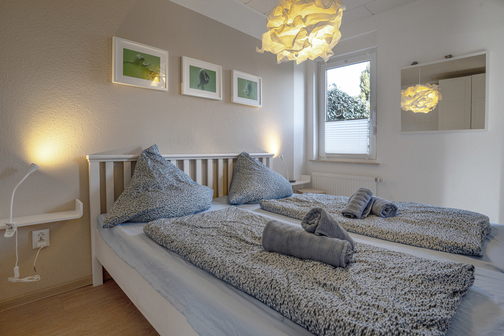 Doppelbett im Schlafzimmer mit dekorativen Decken und Handtüchern.