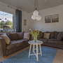 Wohnzimmer mit braunen Sofas, Couchtisch und großen Fenstern.