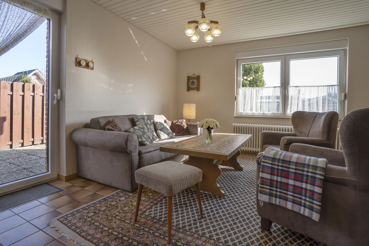 Gemütliches Wohnzimmer mit Sofas, Sesseln und großem Fenster.