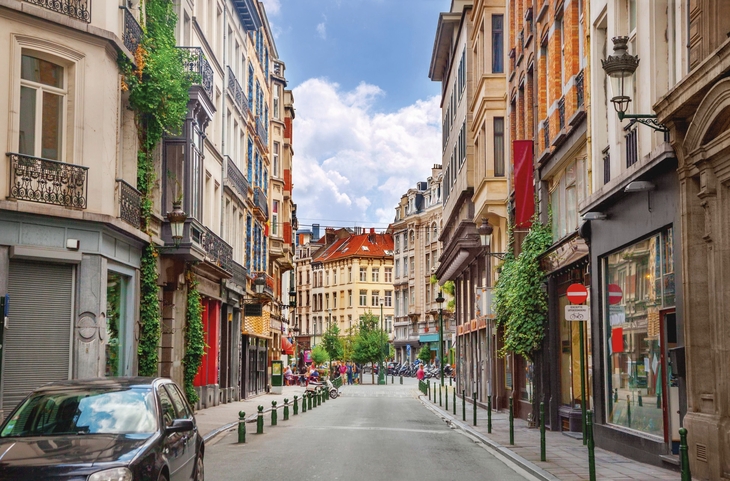 Schmale Straße in Brüssel mit bunten Gebäuden und Fußgängern.