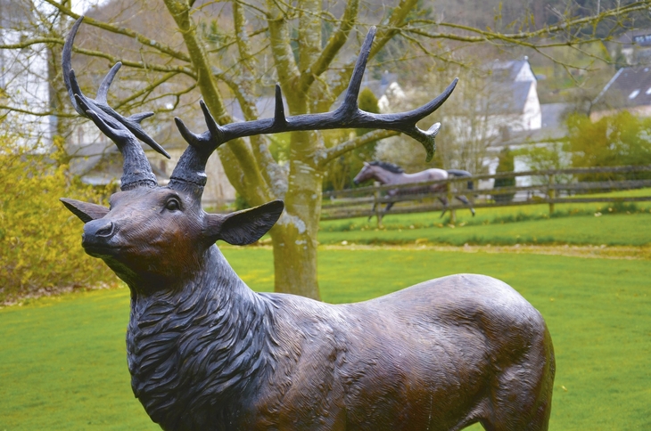Bronzestatue eines Hirsches im Skulpturenpark vor unscharfem Hintergrund.