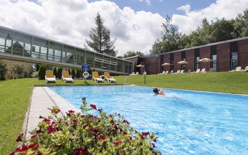 Außenpool des Waldhotels Altenberg, ein Schwimmer im Wasser, Liegestühle am Beckenrand.