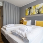 Modernes Hotelzimmer mit zwei Betten, gelben Kissen und abstraktem Kunstwerk.