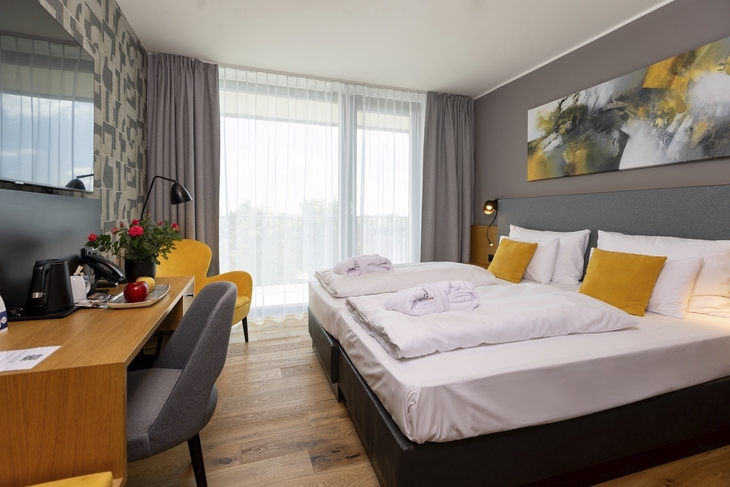 Hotelzimmer mit Doppelbett, Schreibtisch und moderner Einrichtung.