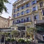 Fassade des Hotel Monsigny in Nizza mit Café-Terrasse und Straßenszene.