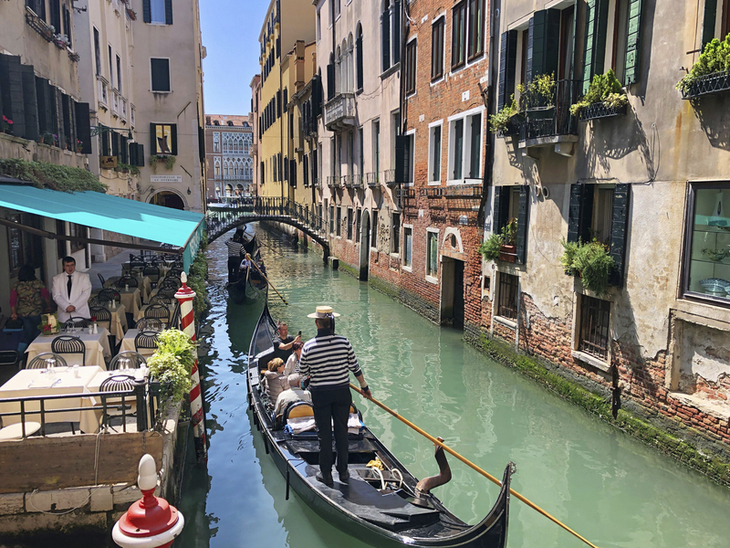 Gondel auf einem Kanal in Venedig mit umliegenden Gebäuden und Café.