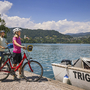 Radfahrer am Bleder See mit Blick auf die Wallfahrtskirche auf Insel.