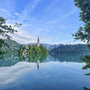 Kirche auf Insel im Bleder See, umgeben von Wasser und bewaldeten Hügeln.