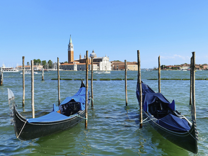Zwei Gondeln auf einem Kanal mit Kirche im Hintergrund in Venedig.