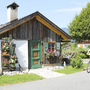 Radfahrer vor einem kleinen Holzhaus mit Blumen am Tauernradweg.