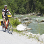 Radfahrer auf Schotterweg entlang der Salzach im Grünen