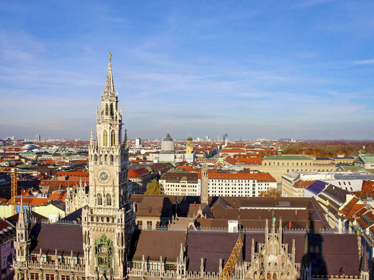 Blick auf das Münchner Rathaus mit Stadt im Hintergrund bei klarem Himmel.