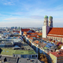 Blick über München mit der Frauenkirche bei klarem Himmel.