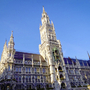 Münchens Neues Rathaus bei Tageslicht vor blauem Himmel.